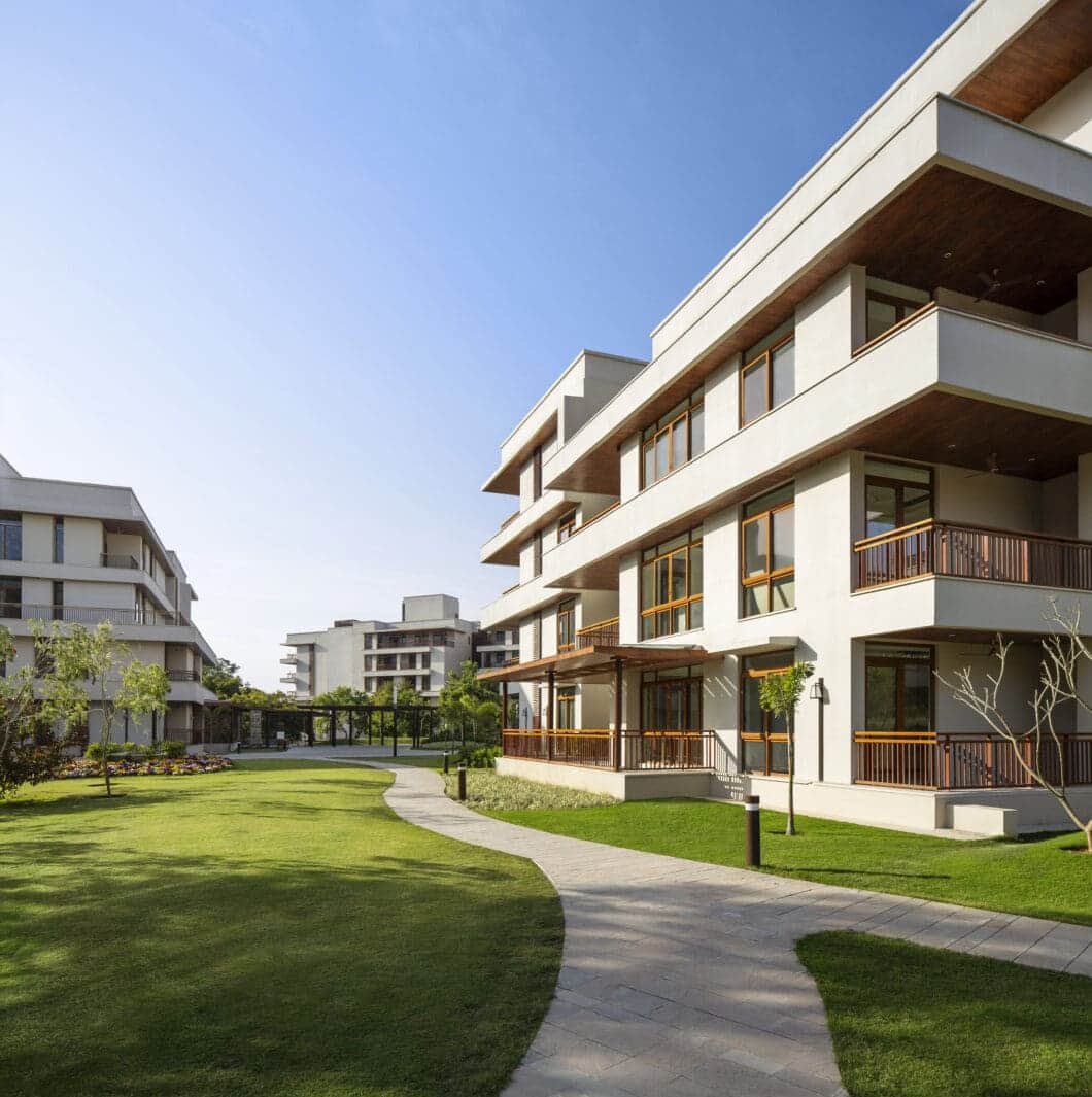 Antara Senior Living residences in the Purukul foothills, cream and timber facades opening onto a lawn with a curving path.