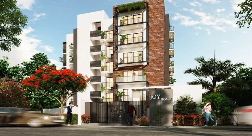 Kwality Joy Homes on Patel Road, five storey block with white stucco and exposed brick facade under mature trees.
