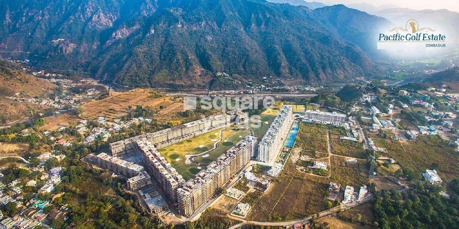 Aerial view of Pacific Golf Estate on Sahastradhara Road, seven residential towers ringing a green with mountain slopes beyond.
