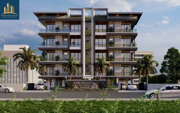 Pari Heights apartment building near Laxman Chowk, four floor block with stone accents and mature palms flanking the entrance gate.
