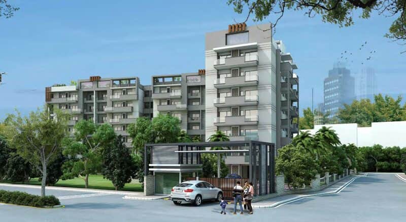 Yash Greens on Saharanpur Road, three residential towers behind a landscaped entrance drive with a family walking past.